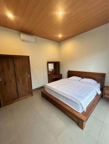 a bedroom with a large bed with a wooden headboard at Villa Teduh Canggu in Dalung