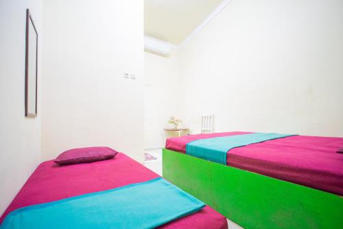 two beds with colorful sheets in a room at Omah Simbah Malioboro in Ngabean