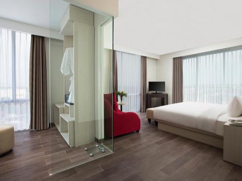 une chambre d'hôtel avec un lit et un fauteuil rouge dans l'établissement Hotel Santika Pekalongan, à Pekalongan