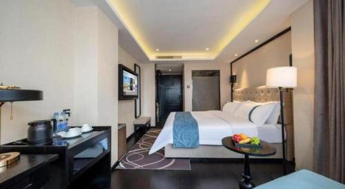 a hotel room with a large bed and a desk at Xana Hotelle Wuxi Railway Station Zhongshan Road in Wuxi