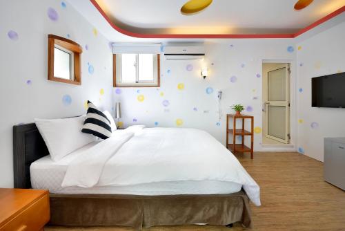 a bedroom with a white bed and a flat screen tv at Kenting 166 in Kenting