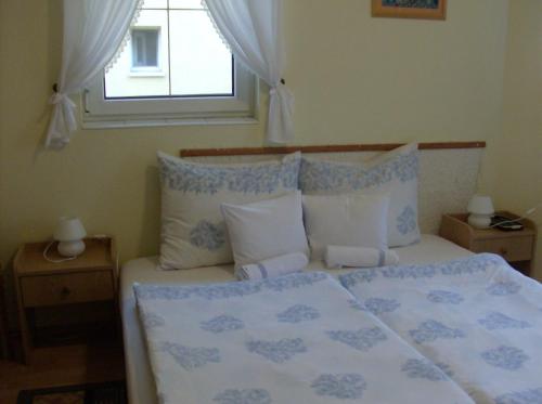 1 cama con almohadas azules y blancas y ventana en Zsuzsanna Ház, en Hévíz