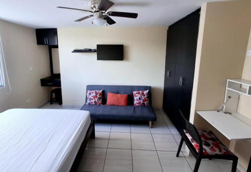 a bedroom with a blue couch and a ceiling fan at Tonsupa Beach in Tonsupa