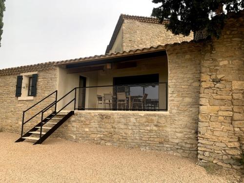 - un bâtiment en pierre avec un balcon et un escalier dans l'établissement Le gîte de Figon, à Laudun-l'Ardoise