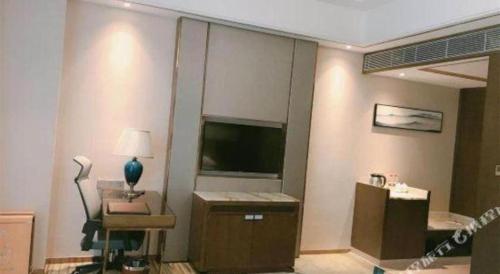 a living room with a television and a chair and a lamp at Venus Royal Hotel Nanning East High-Speed Railway Station in Nanning