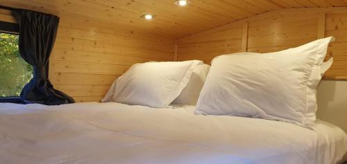 a bed with white pillows in a wooden room at The Field View by Tiny Away in Egerton