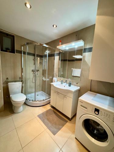 a bathroom with a shower toilet and a washing machine at Infinity Apartment Blue Horizont Przno in Budva