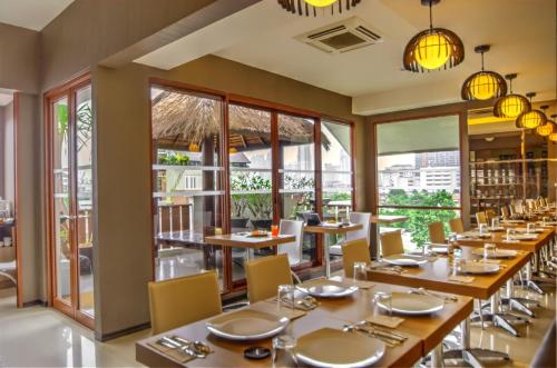 restauracja z drewnianymi stołami i krzesłami oraz dużymi oknami w obiekcie Rasuna Mansion w Dżakarcie