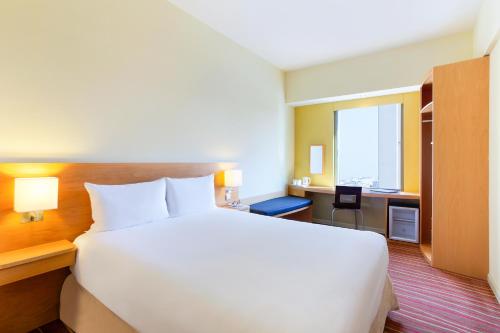 a bedroom with a large white bed and a desk at ibis Deira Creekside Dubai in Dubai