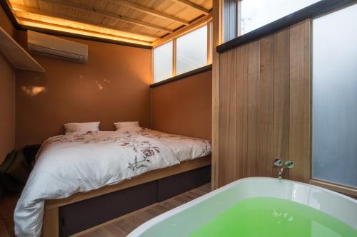a small bathroom with a bed and a tub at Machiya Maya Gion in Kyoto