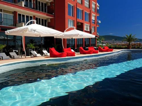 サニービーチにあるPSB Apartments Hotel Heavenの赤い椅子とパラソル付きのスイミングプール