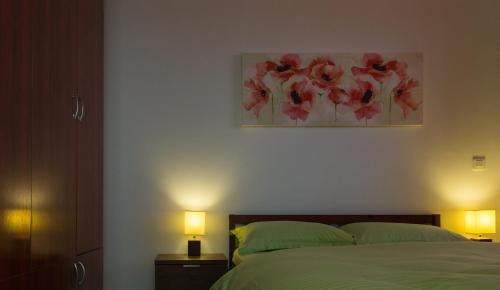 クルジュ・ナポカにあるAdrianApartments ViVaのベッドルーム1室(ランプ2つ、絵画付)