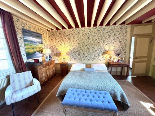 a bedroom with a bed and a chair in it at Le Manoir familial du Quesnot, idéal familles et amis in Lessard-et-le-Chêne