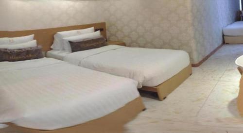 two beds in a hotel room with white sheets at Harbour Bay Hotel in Hong Kong