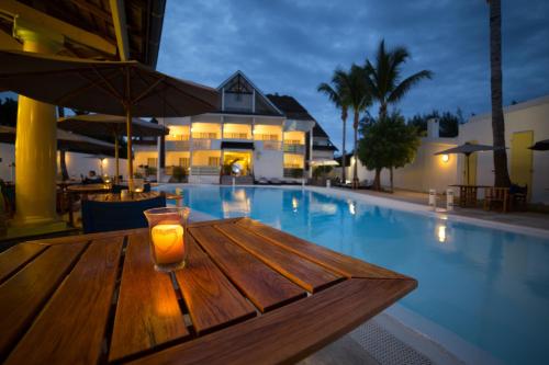 a candle on a wooden table next to a swimming pool at Le Nautile Beachfront in Saint-Gilles les Bains