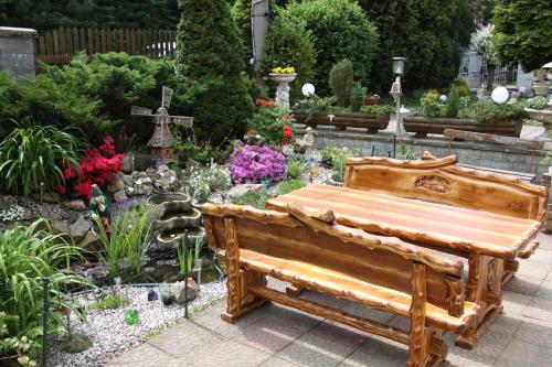 un banco de madera en un jardín con flores en Villa Anastazis - Penzion Eden, en Karlovy Vary