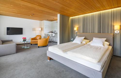 a bedroom with a large bed and a living room at Stella Swiss Quality Hotel in Interlaken