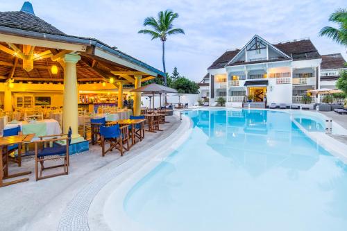 a resort pool with tables and chairs and a restaurant at Le Nautile Beachfront in Saint-Gilles les Bains