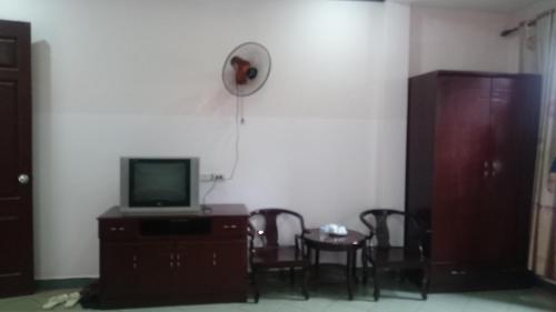 un soggiorno con TV, tavolo e sedie di Hai Duong Guesthouse a Hòa Bình