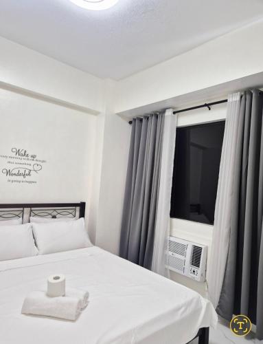 ein Schlafzimmer mit einem weißen Bett und einem Fernseher in der Unterkunft Modern Minimalist 1BR Condotel at BGC Taguig in Taguig