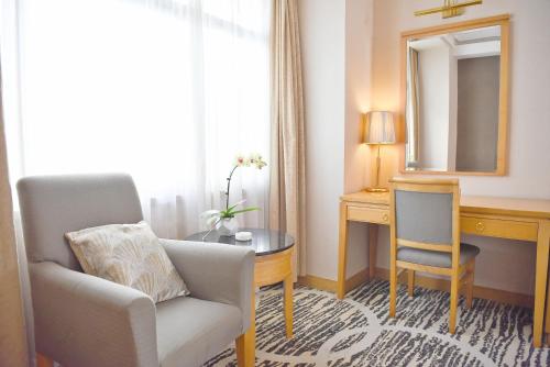 a living room with a chair and a desk and a mirror at Baiyun Hotel Guangzhou in Guangzhou