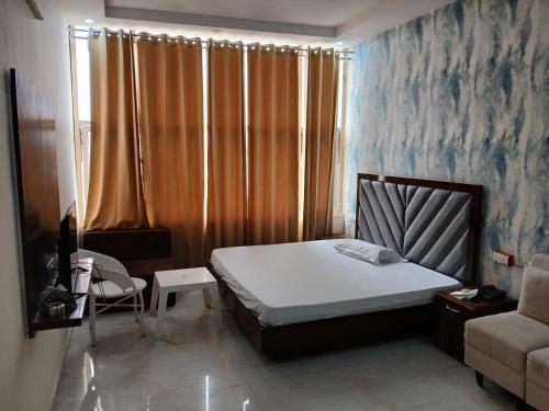 齐拉克普尔Hotel Golden Rooftop的一间卧室，里面有一张床、一把椅子和一扇窗户