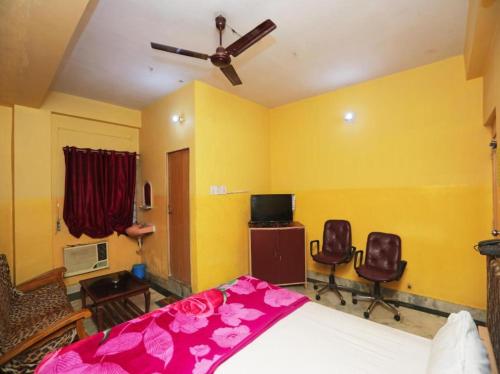 a bedroom with a bed and two chairs and a ceiling fan at HOTEL S-A-V-I-T-R-I PALACE Near Shree Baba Baidyanath Jyotirlinga - Free Wifi And Parking Facilities - Spacious and Fully Air Conditioned Rooms-Budget Hotel in Deoghar