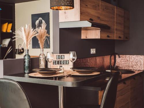 une cuisine avec une table noire avec des assiettes et des verres dans l'établissement Atelier du chill - Bergues, à Bergues