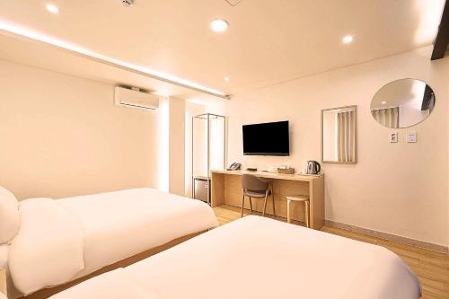 a hotel room with two beds and a desk at H Avenue Chuncheon in Chuncheon