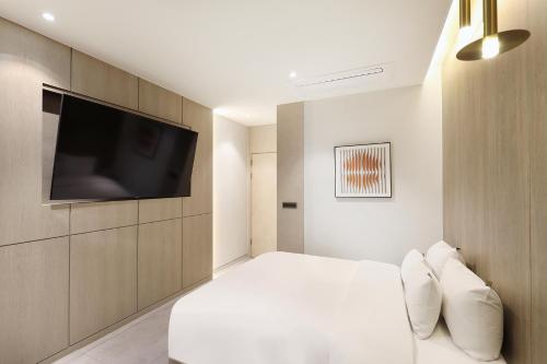 a bedroom with a white bed and a flat screen tv at Hound Hotel Asan Terminal in Asan