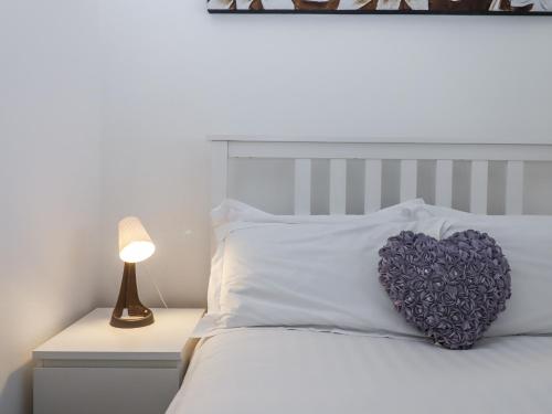a heart pillow on a bed with a lamp at Driftwood in Torquay