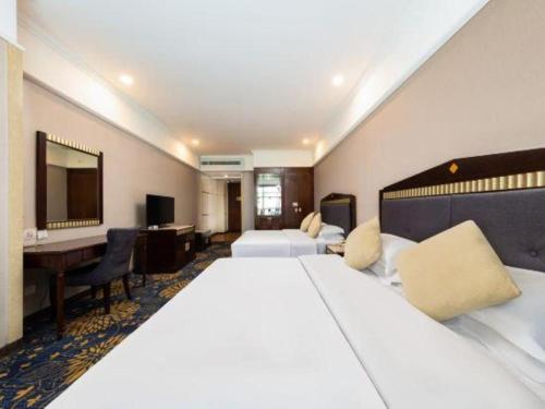 a hotel room with two beds and a desk at Zhongshan Hui Quan Hotel in Zhongshan