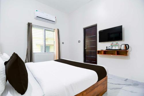 a bedroom with a bed and a tv on a wall at Hotel O VIP Road Near Golden Beach in Puri