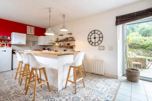 a kitchen with a white counter and stools at Gîte avec piscine-Cap Sizun in Confort