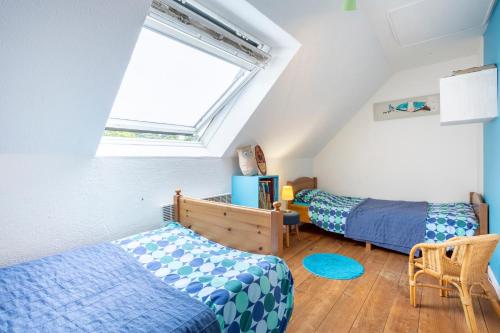 a attic bedroom with two beds and a window at Gîte avec piscine-Cap Sizun in Confort
