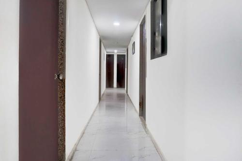 a hallway with white walls and a white tile floor at Hotel O Talwade in Pune