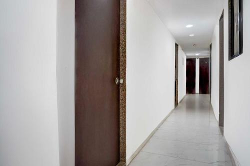 a hallway with white walls and a brown door at Hotel O Talwade in Pune