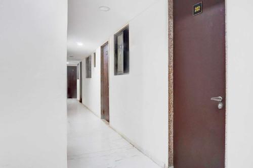a hallway with white walls and a brown door at Hotel O Talwade in Pune