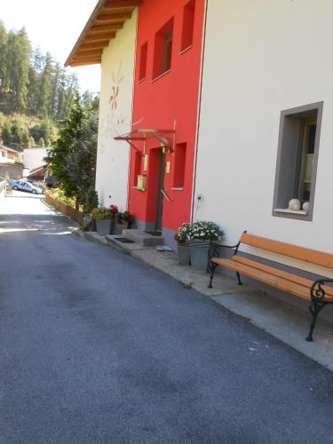 a bench in front of a building with a red door at Haus Sagl in Nauders