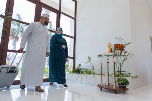 a man and a woman standing in a room with a suitcase at Al Shatti Villas in Salalah