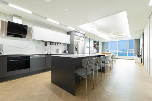 a kitchen with white cabinets and a bar with chairs at Brown Suites Busan Station in Busan