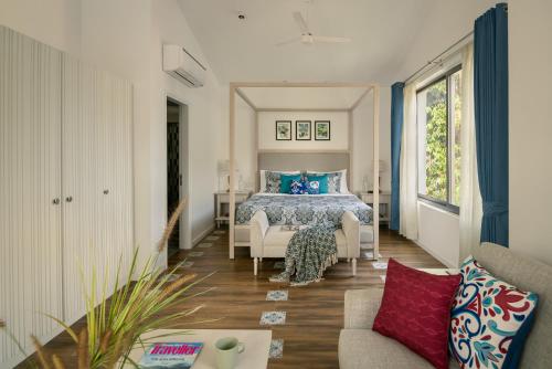 a bedroom with a bed and a couch at Kensho Hibiscus 3-BHK Villa With Common Pool, Plunge Pool & Lift Near Popular Beaches in Majorda