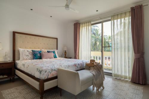a bedroom with a bed and a chair and a window at Kensho Hibiscus 3-BHK Villa With Common Pool, Plunge Pool & Lift Near Popular Beaches in Majorda