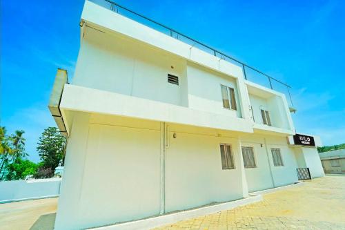 a large white building with two garage doors at Hotel O Kureepuzha Kollam in Kollam