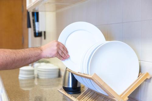 a man holding a stack of plates in a dishwasher at Al Shatti Villas in Salalah