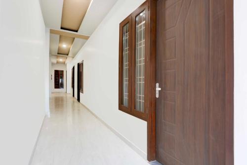 a corridor with a wooden door and white walls at Collection O Bareilly Near Satellite Bus Stand in Bareilly