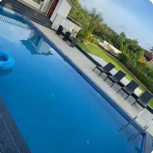 a blue swimming pool with chairs in a house at Skylands Homes in Calangute
