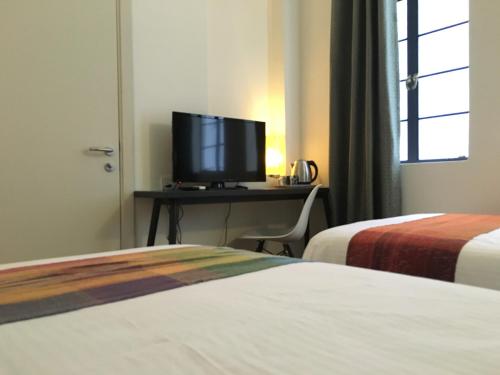 a hotel room with two beds and a desk with a television at Spices Hotel in George Town