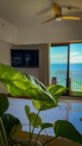 a green plant in a bedroom with a view of the ocean at Aqua Horizon Beachside Condo I Signature Art Suites in Dauis