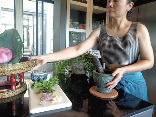 a woman standing in a kitchen preparing plants in vases at Chombua MaeWang ชมบัว in Chiang Mai